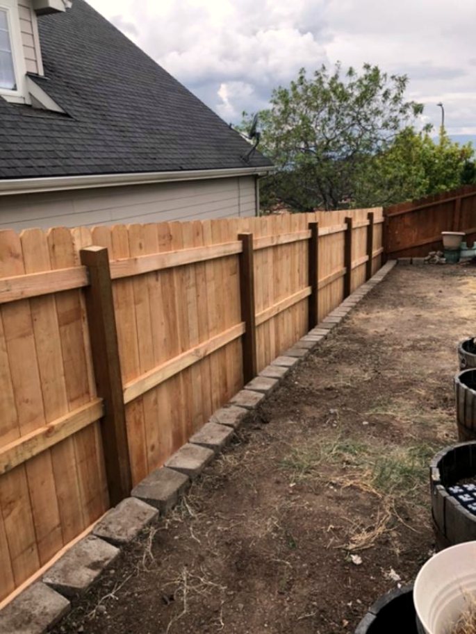 Cedar fence meeting a stone border in a residential garden, Rogue Valley Oregon